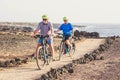 Couple of two seniors riding bikes together on the ground having fun - doing exercise to be healthy and fit