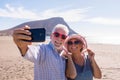 Couple of two seniors taking a selfie together at the beach having fun in their vacations - happy mature old people smiling and