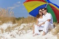 Couple Under Colorful Umbrella on Beach Royalty Free Stock Photo