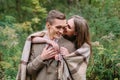 Couple under the plaid in an autumn romantic forest. Autumn wedding outdoors.