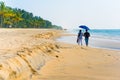 Couple under umbrella walk on Marari Beach