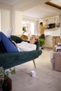 Couple Unpacking Boxes After Moving Into New Home Together As Woman Lies On Sofa Using Laptop Royalty Free Stock Photo