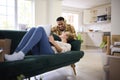 Couple Unpacking Boxes After Moving Into New Home Together As Woman Lies On Sofa Using Laptop Royalty Free Stock Photo