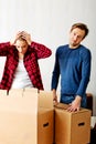 Couple unpaking boxes, woman looking to inside and aghast holding her head Royalty Free Stock Photo