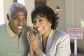 Couple Using Cell Phone In Front Of New House