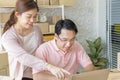 Couple using laptop at home. Pointing at screen with happily