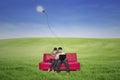 Couple using laptop on red sofa with lamp outdoor