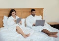 Couple Using Laptop And Tablet Sitting In Bed At Home Royalty Free Stock Photo