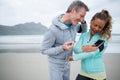Couple using mobile phone while listening music on beach Royalty Free Stock Photo