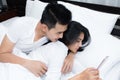 Couple using smartphone on the bed in the morning