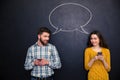 Couple using smartphones over blackboard with speech dialogue