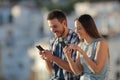 Couple using their smart phones in a town at sunset Royalty Free Stock Photo