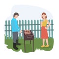 A couple on vacation. Man cooks shish kebab, grills meat. The girl is drinking a cocktail. On the green lawn, against a wooden