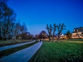 Couple Walk on a pathway in moonlight on a winter evening with a big cutted tree on the green grass in nature at the riverside