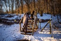 Couple walking across wooden steps in snowy winter landscape with sunlight Royalty Free Stock Photo