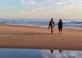Couple Walking Along a Peaceful Beach at Sunset Royalty Free Stock Photo