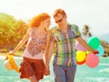 Couple walking on the beach with air colored balls.