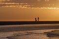 Couple walking on the beach with dog at sunrise