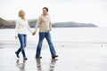 Couple walking on beach holding hands smiling Royalty Free Stock Photo