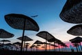 Couple walking on the beach at sunrise with cromatic umbrella and beautiful colors in background