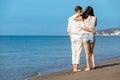 Couple walking on beach. Young happy interracial couple walking on beach smiling holding around each other. Royalty Free Stock Photo