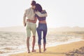 Couple walking on beach. Young happy interracial couple walking on beach smiling holding around each other. Royalty Free Stock Photo