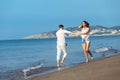 Couple walking on beach. Young happy interracial couple walking on beach smiling holding around each other. Royalty Free Stock Photo