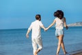 Couple walking on beach. Young happy interracial couple walking on beach smiling holding around each other. Royalty Free Stock Photo