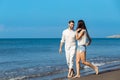 Couple walking on beach. Young happy interracial couple walking on beach smiling holding around each other. Royalty Free Stock Photo