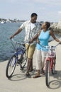 Couple Walking With Bicycles And Looking At Each Other On Beach Royalty Free Stock Photo