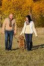 Couple walking dog in autumn sunny park Royalty Free Stock Photo