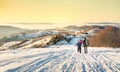 Couple walking down the snowy mountain in sunset time Royalty Free Stock Photo