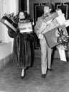 Couple walking and holding stacks of presents Royalty Free Stock Photo