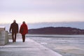 Couple walking on a long pier, by sunset on a beautiful winter day. Royalty Free Stock Photo