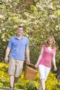 Couple walking outdoors with picnic basket smiling Royalty Free Stock Photo