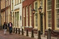 Couple walking on street with elegant semidetached brick buildings on cloudy day in Delft.