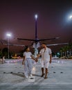 Couple walking on the street in Thailand with airplane on the background , Pattaya Thailand sunset