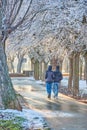 Couple walking, taking a stroll in a tree surrounded by snow at sunset. Winter sunset with unrecognisable people, rain and sun