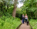 Happy couple walking their dog on the wooden boardwalk near the RIver Bure in Wroxham, Norfolk, UK