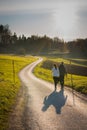 A couple is walking together on an asphalt road towards the sunset on a cold autumn evening with sunset just about to happen. Easy Royalty Free Stock Photo