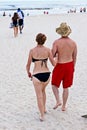 A couple walks arm in arm along the beach