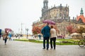 A couple walks around the city under one umbrella while it\'s raining