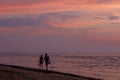 Couple walks barefoot along sea coast during colorful sunset. Jurmala beach, Baltic seaside, Latvia.