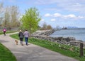 A couple walks a dog as a cyclist rides by on Toronto`s waterfront trail Royalty Free Stock Photo