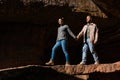 a couple walks hand in hand through a rocky landscape, the girl leading the boy.