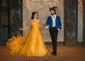 Couple walks in room old castle. Happy beauty woman fantasy princess in yellow dress and guy enchanted beast, horns on