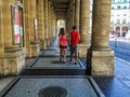 Couple walks under Comedie Francaise arcade in Paris