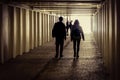 A couple walks in the underpass with a group of girls at the entrance