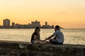 Couple on wall at Malecon in sunset Havana