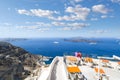 A couple watches cruise ships leave the port from a terrace overlooking the Aegean Sea at Thira, on the island of Santorini Greece